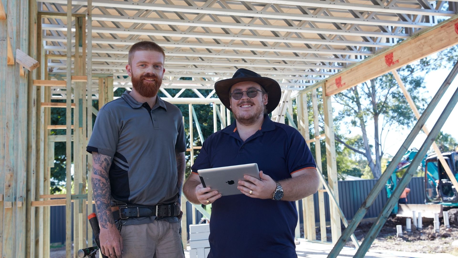 Two Master Builders members in a half built house smile at the camera